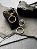 A pair of silver link earrings, with one smaller circle and one larger circle, connected by a gold-toned chunky link.