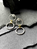 A pair of silver link earrings, with one smaller circle and one larger circle, connected by a gold-toned chunky link.