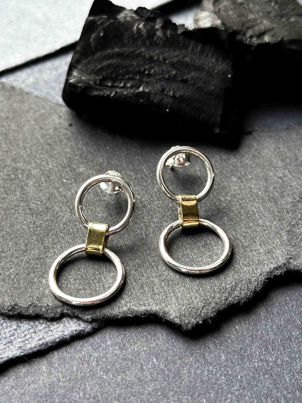 Two solid silver circles joined by a chunky brass link. Understated contemporary drop stud earrings.