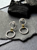 Two solid silver circles joined by a chunky brass link. Understated contemporary drop stud earrings.