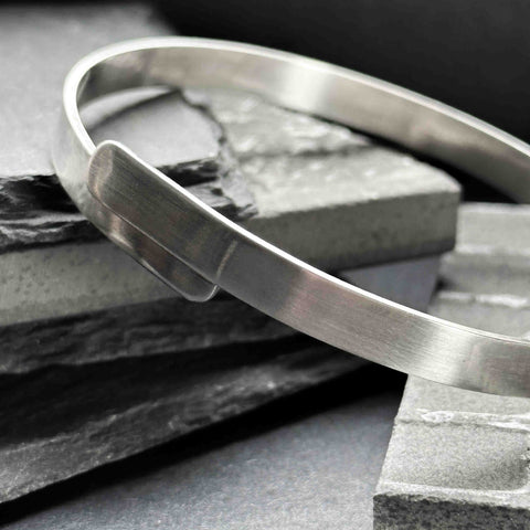 Chunky sleek sterling silver bangle with a matte finish. Simple minimalist bangle with central overlapping detail.