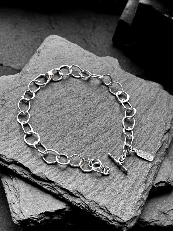 Molten asymmetrical skinny link sterling silver bracelet with single chunky contrasting oval link and T-bar toggle clasp