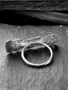 A large, rectangular textured silver ring with a ripped, organic edge and rippling molten texture.