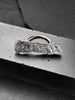A large, rectangular textured silver ring with a ripped, organic edge and rippling molten texture.